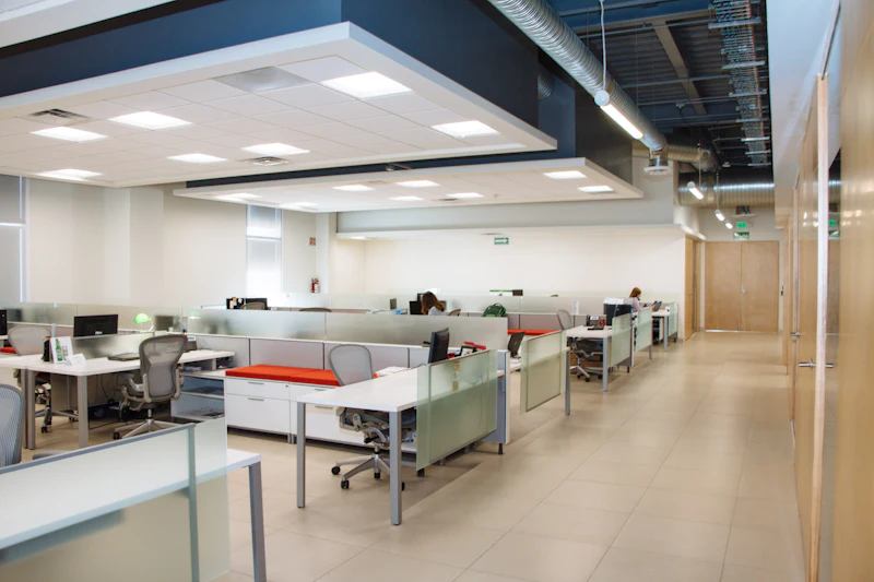 An open-plan floor of workstations laid out in even bays under a bright ceiling