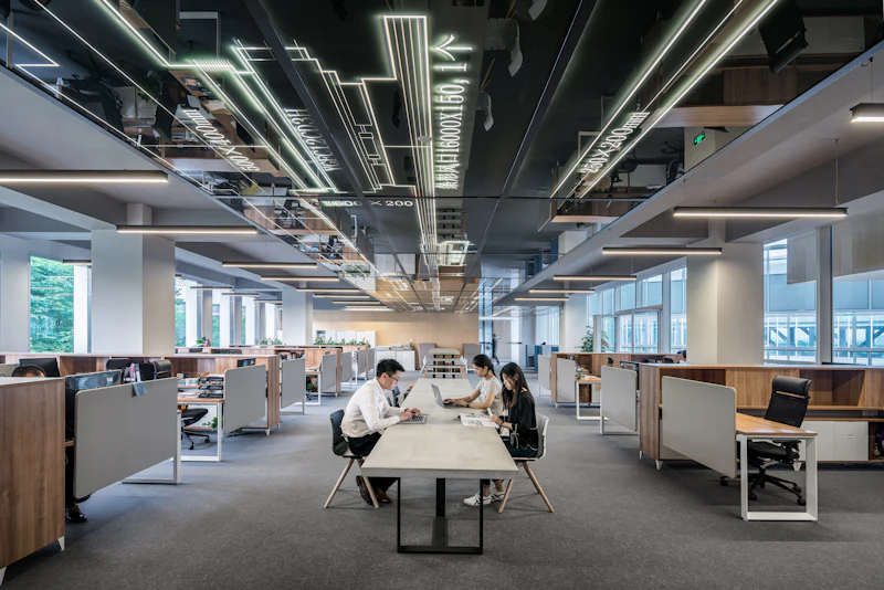 A completed office floor with exposed services overhead and rows of desks below