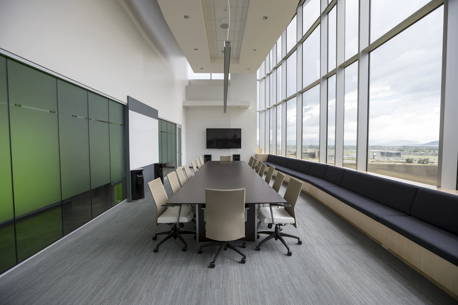 A long boardroom table running the length of a glazed meeting room