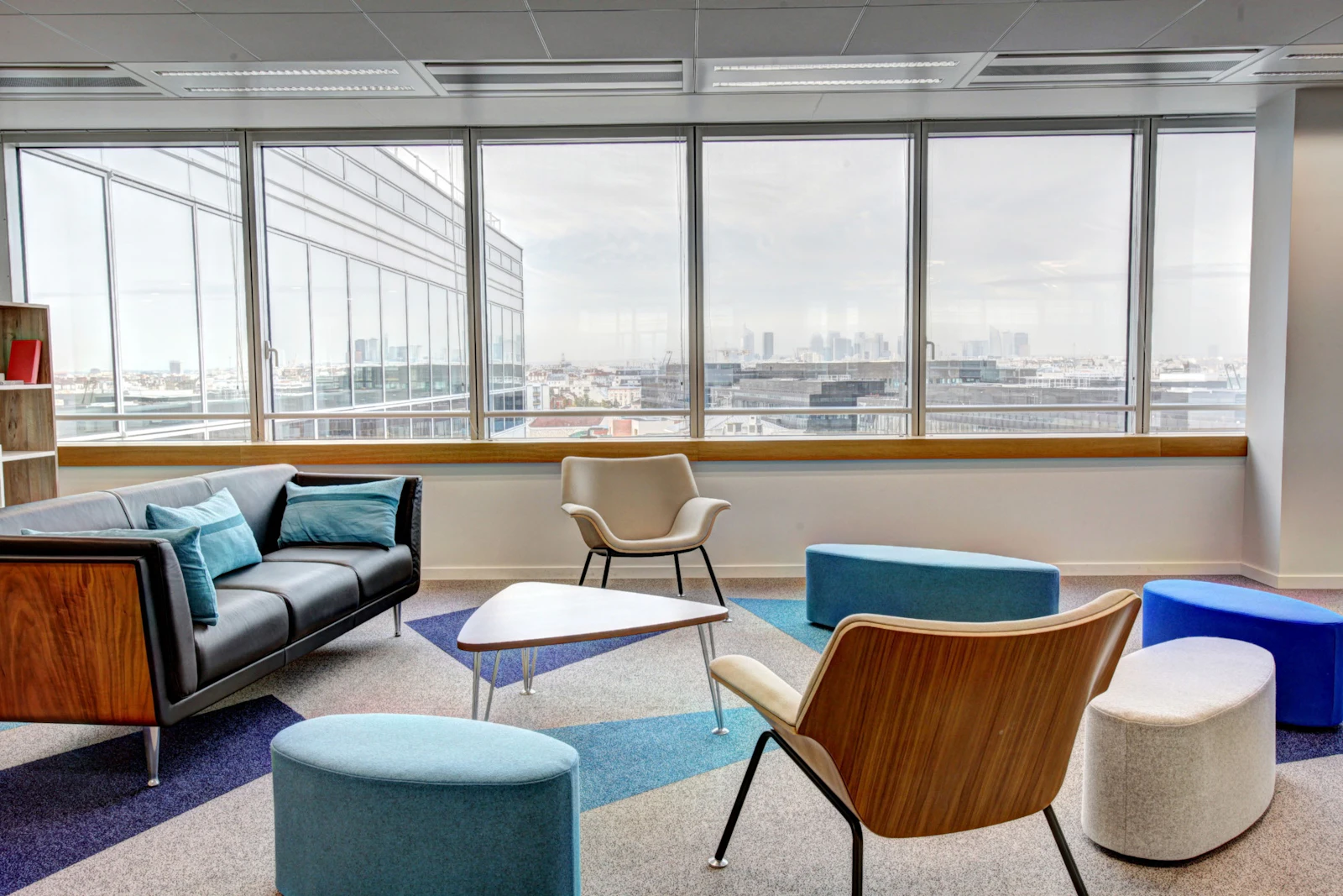 A perimeter breakout area with loose furniture and city views along the glazing